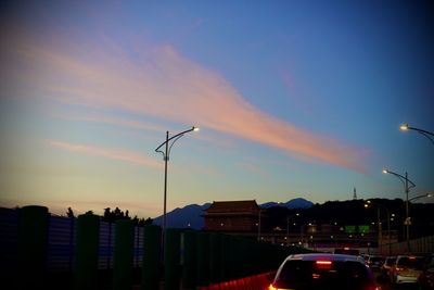 Street lights in city against sky during sunset