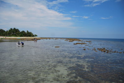 Men in sea against blue sky