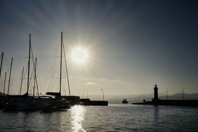 Silhouette boats moored in river on sunny day