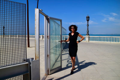 Portrait of woman walking at doorway against blue sky