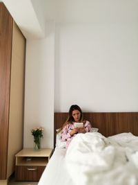 Woman on bed using digital tablet at home