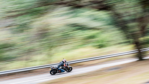 Blurred motion of man riding motorcycle on road