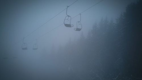 Overhead cable car against sky during foggy weather