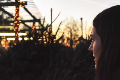 Side view of young woman looking away at sunset
