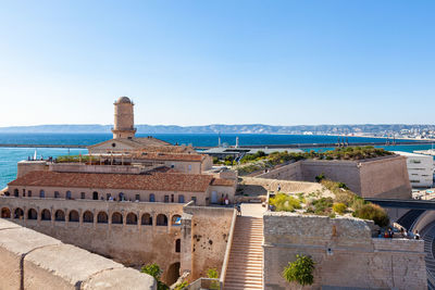 Buildings by sea against clear blue sky