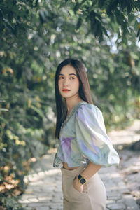 Beautiful young woman looking away while standing in park