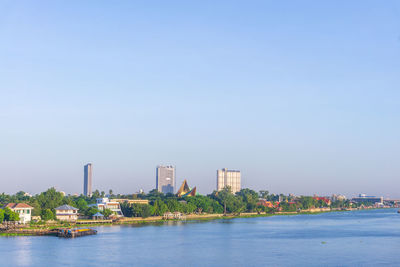 Sea by buildings against clear sky
