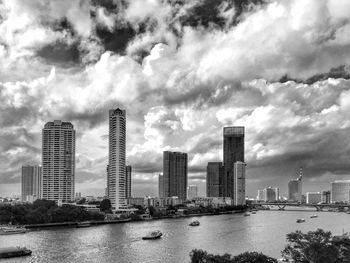 City at waterfront against cloudy sky