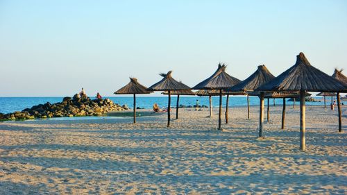 Parasols at beach against clear sky on sunny day