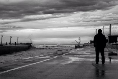 People on beach against cloudy sky