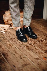 Low section of man wearing formal shoes while standing on wooden floor