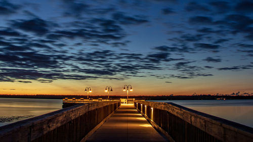 Pier over sea against sky during sunset