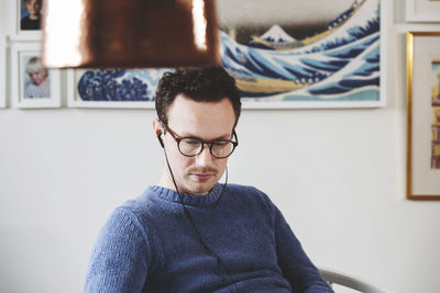 Concentrated man listening music while sitting on chair at home