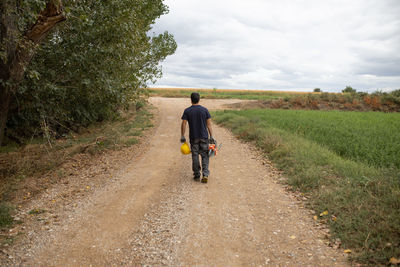 Rear view of man riding bicycle on road against sky