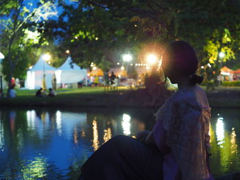 Woman sitting by lake at night