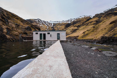 Built structure by lake and buildings against sky