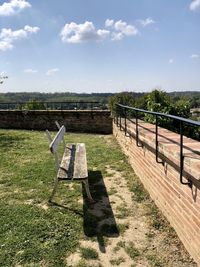 Bench on field against sky