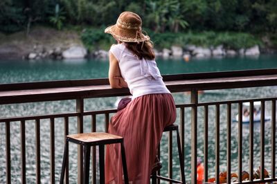 Rear view of woman standing by railing