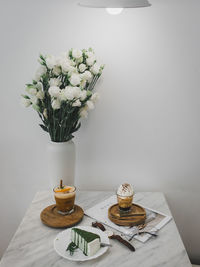 Flower vase on table against white wall