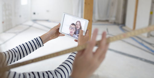 Cropped hand of girl taking selfie at construction site