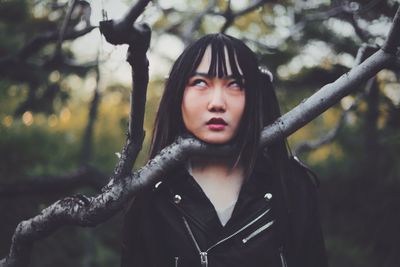 Portrait of beautiful woman standing by tree