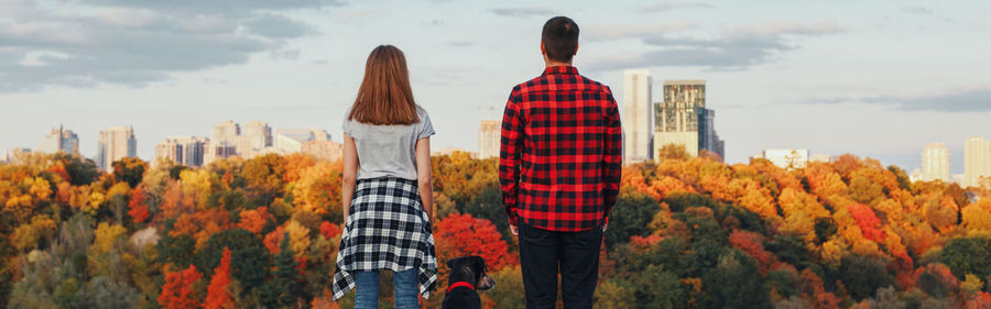 Rear view of couple standing against trees and sky