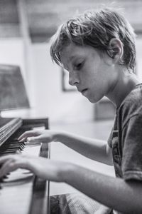 Side view of boy playing piano