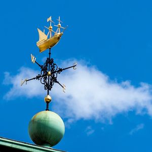 Low angle view of weather vane against blue sky