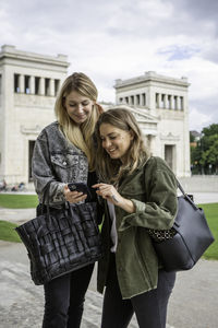 Young woman using mobile phone while standing on camera