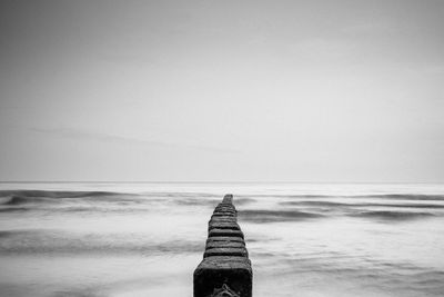 Stone pier on sea against clear sky