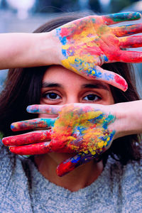 Close-up portrait of woman showing colorful powder paint on hands