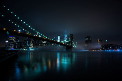 Illuminated bridge over river against sky at night