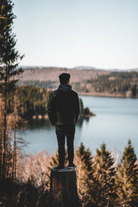 Rear view of man looking at lake against sky