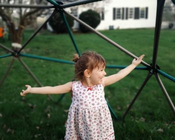 Cheerful girl standing against play equipment at park