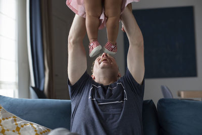 A father laughing and playing with his young biracial daughter