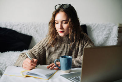 Portrait of a female freelance translator working from home, writing translation in notebook at