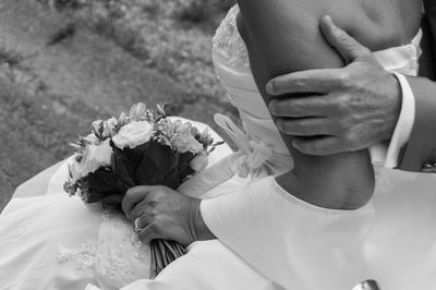 Cropped hand of bride holding bridegroom while walking on footpath