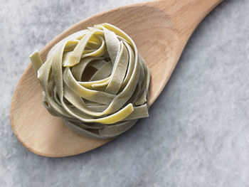 High angle view of tagliatelle pasta on wooden spoon at table