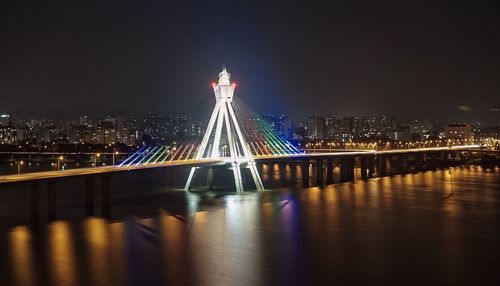 Illuminated golden gate bridge over river against sky at night