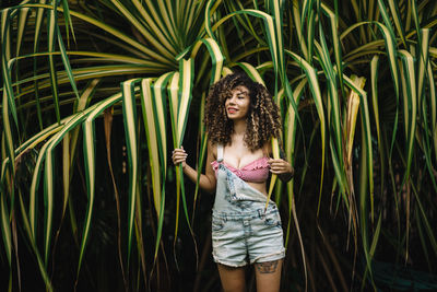 Full length of smiling woman standing against plants
