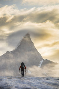 Rear view of person on snowcapped mountain against sky