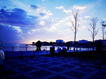 Silhouette woman standing by sea against sky during sunset