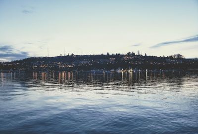 Scenic view of lake against sky in city