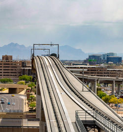 Railroad tracks amidst buildings in city against sky