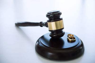 Close-up of gavel with wedding rings on table