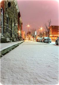 Snow covered street amidst buildings in city