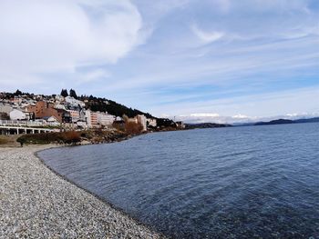 Buildings by sea against sky