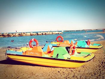 Boats moored on beach against clear sky