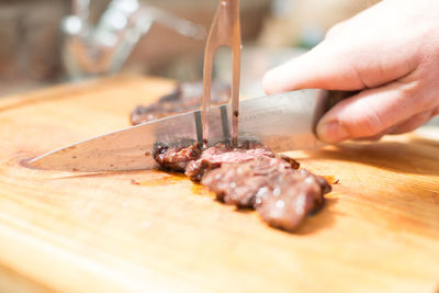 Close-up of hand holding meat on cutting board