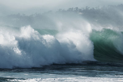 Waves splashing in sea against sky